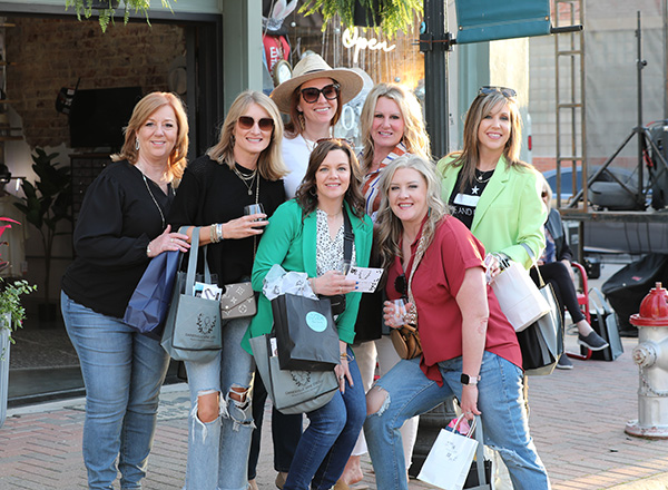 plan-trip-intinerary-img A group of women posing outside of a shop on main street