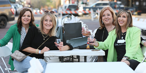 shopping-header-img-mobile Photo of a group of women sitting at an outdoor table posing with their shopping haul.