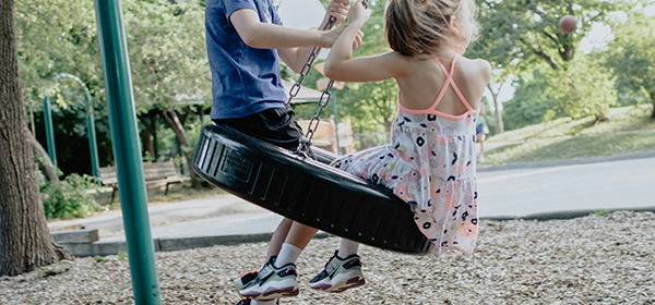 a girl and her brother on a swing set