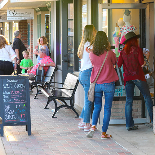 Photo of shoppers looking into store windows on the downtown strip